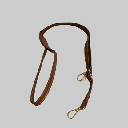 Brown leather lanyard with a metal clip on a gray surface