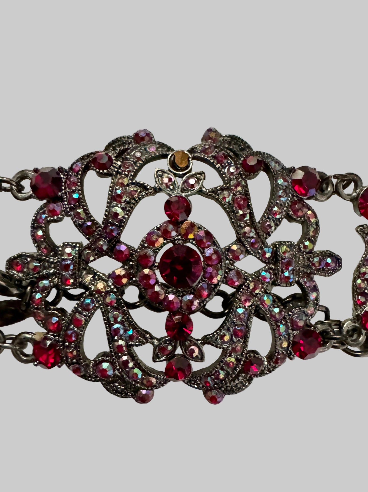 Decorative necklace with red and clear gemstones on a light gray background