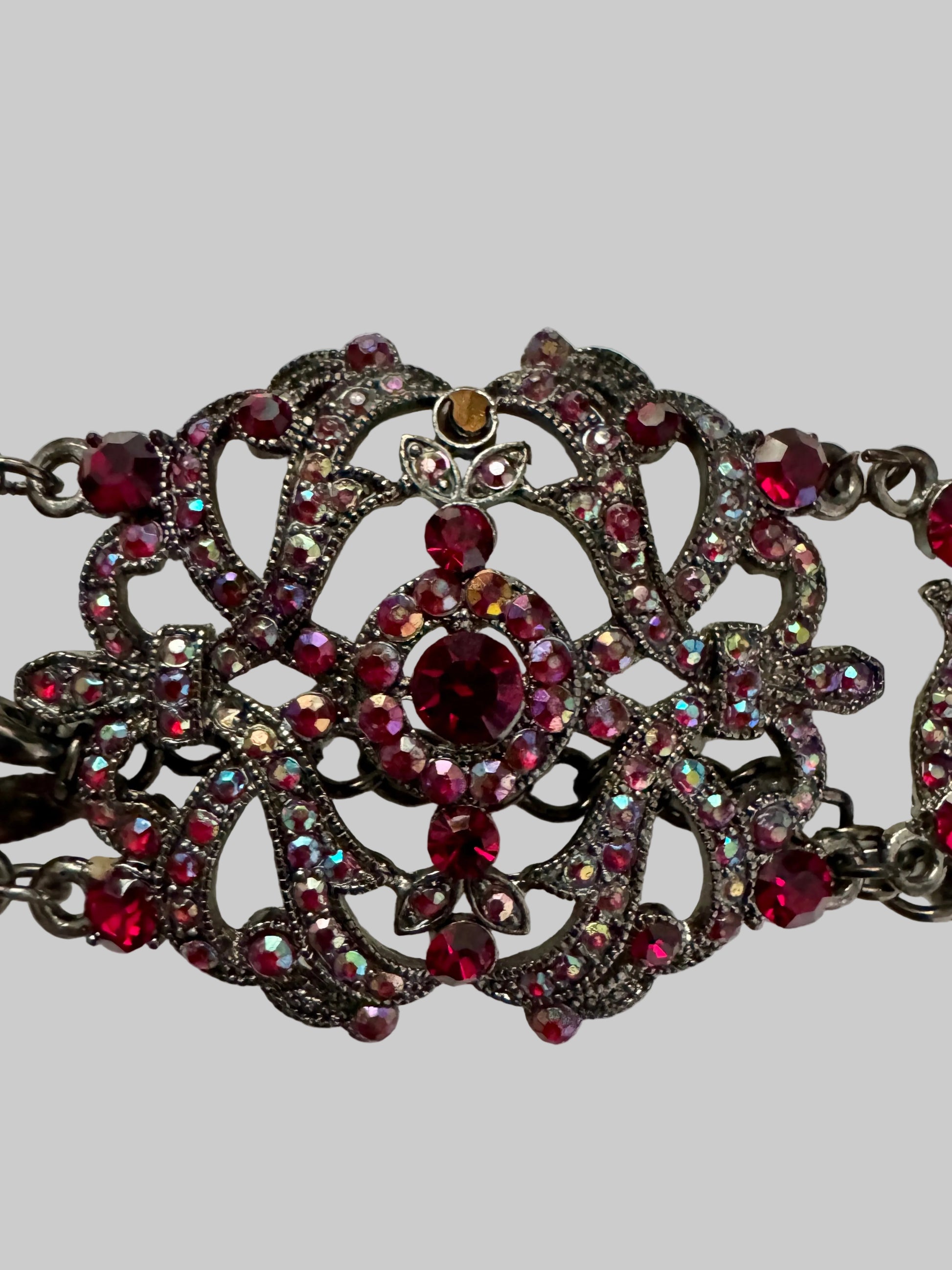 Decorative necklace with red and clear gemstones on a light gray background