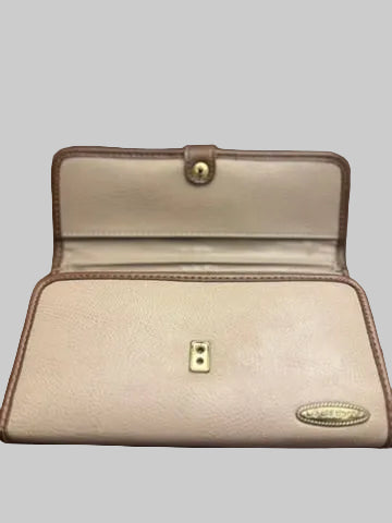 A beige pebbled leather wallet with brown trim, shown open on a dark wooden surface. It features gold-tone metal hardware, including a snap button on the inside flap and a small oval brand plaque on the front.
