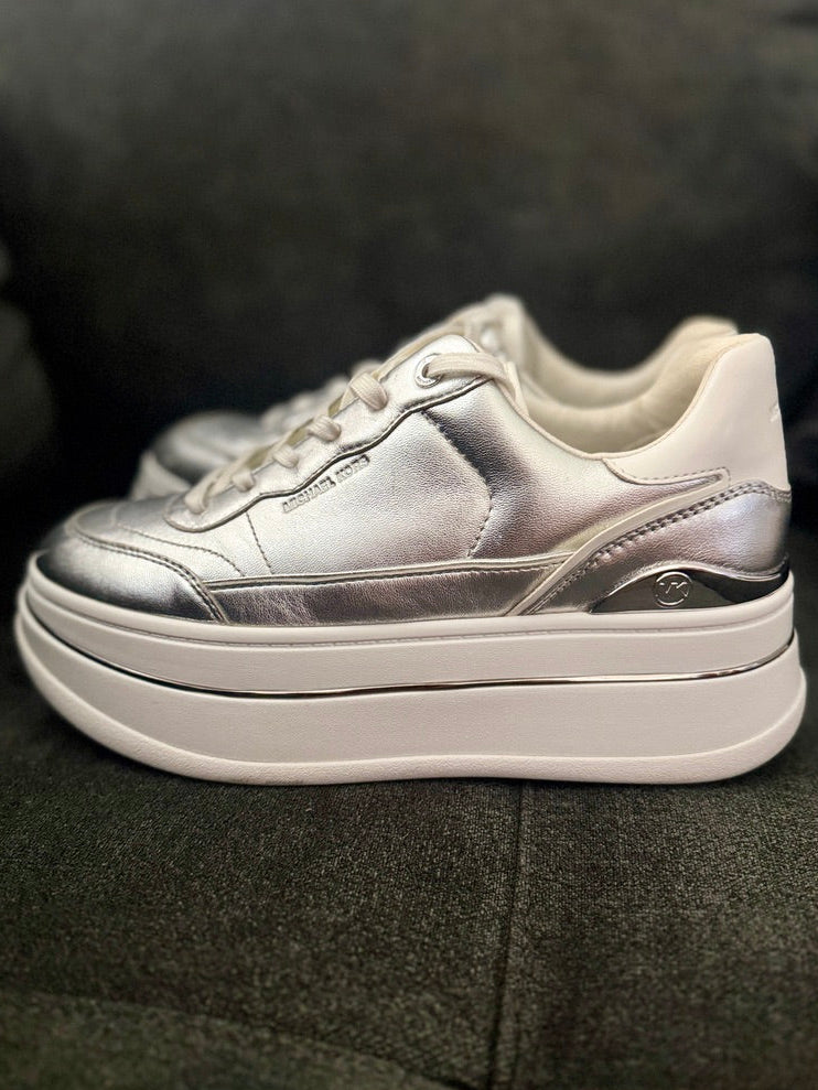 Silver sneakers with white soles on a dark fabric background