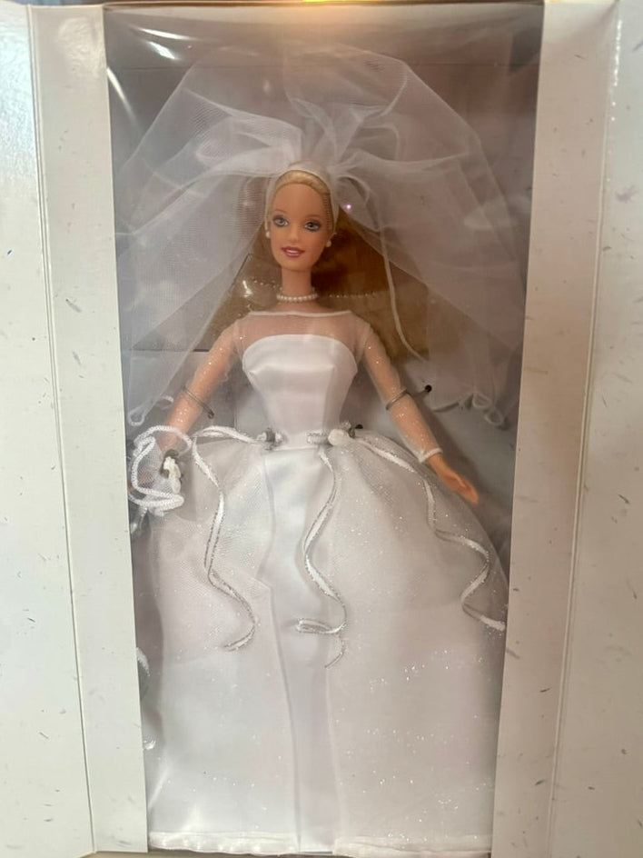 Barbie doll in a wedding dress and veil inside a clear plastic box.