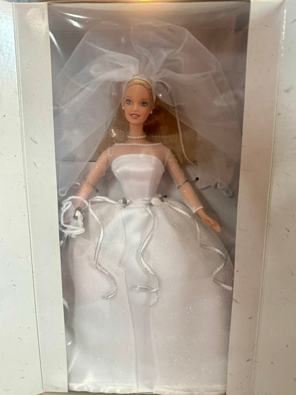Barbie doll in a wedding dress and veil inside a clear plastic box.