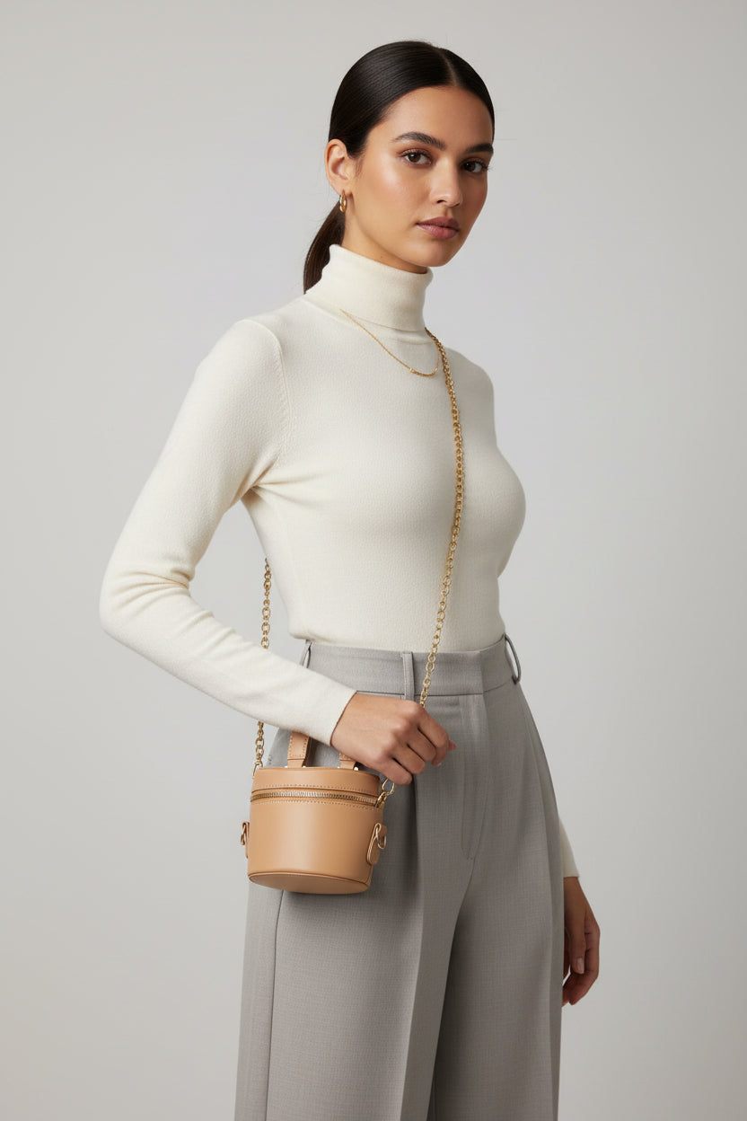 Beige handbag with gold chain on a textured surface