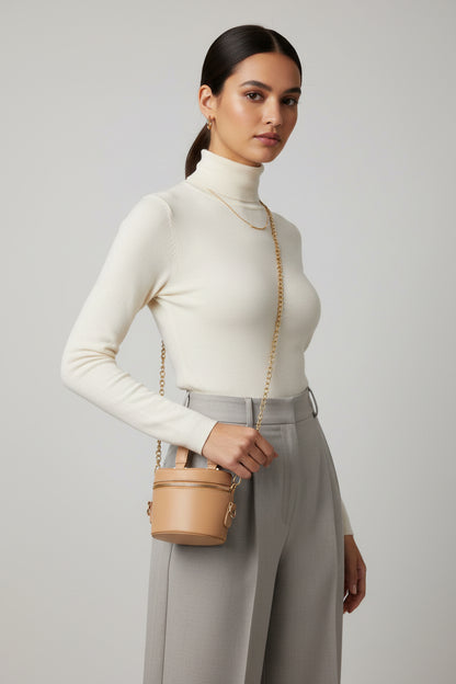 Beige handbag with gold chain on a textured surface