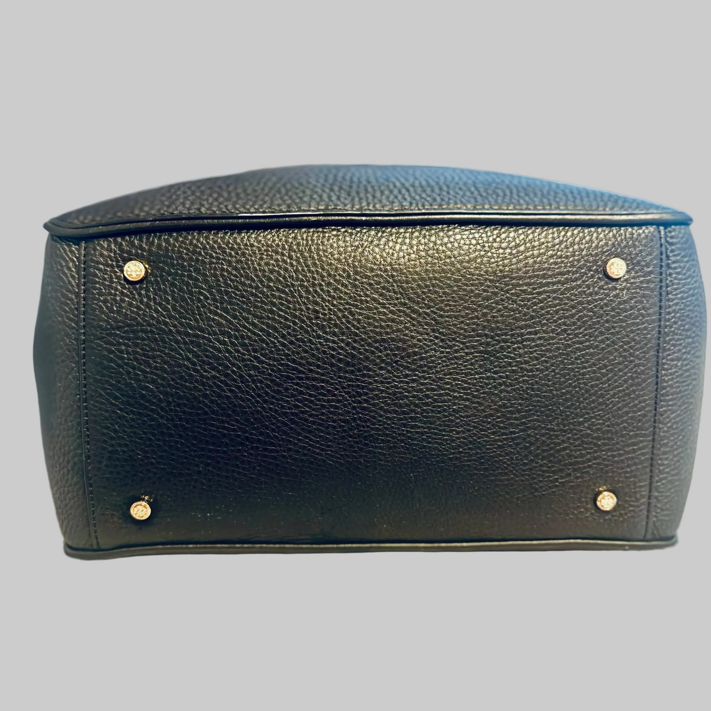 Black leather pouch with gold studs on a light blue background