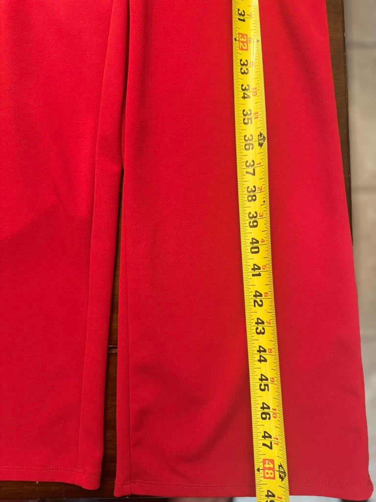 Close-up of red fabric with a yellow measuring tape laid vertically down the center to show dimensions.