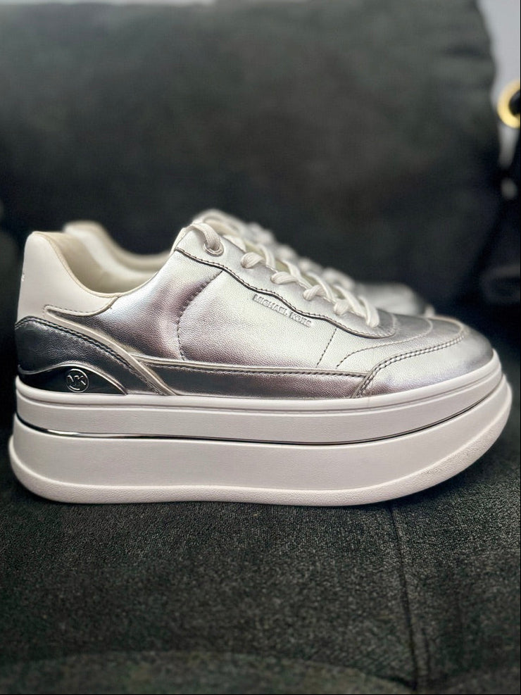 Silver sneaker with a thick white sole on a dark surface