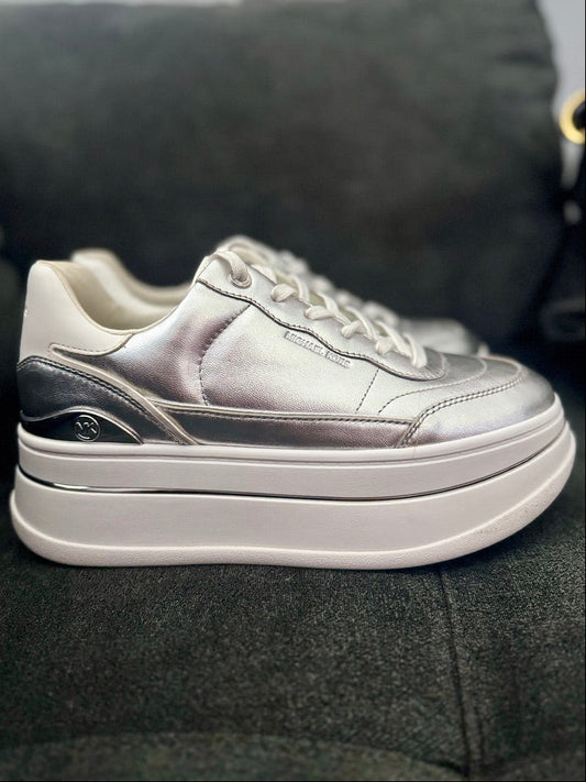 Silver sneaker with a thick white sole on a dark surface