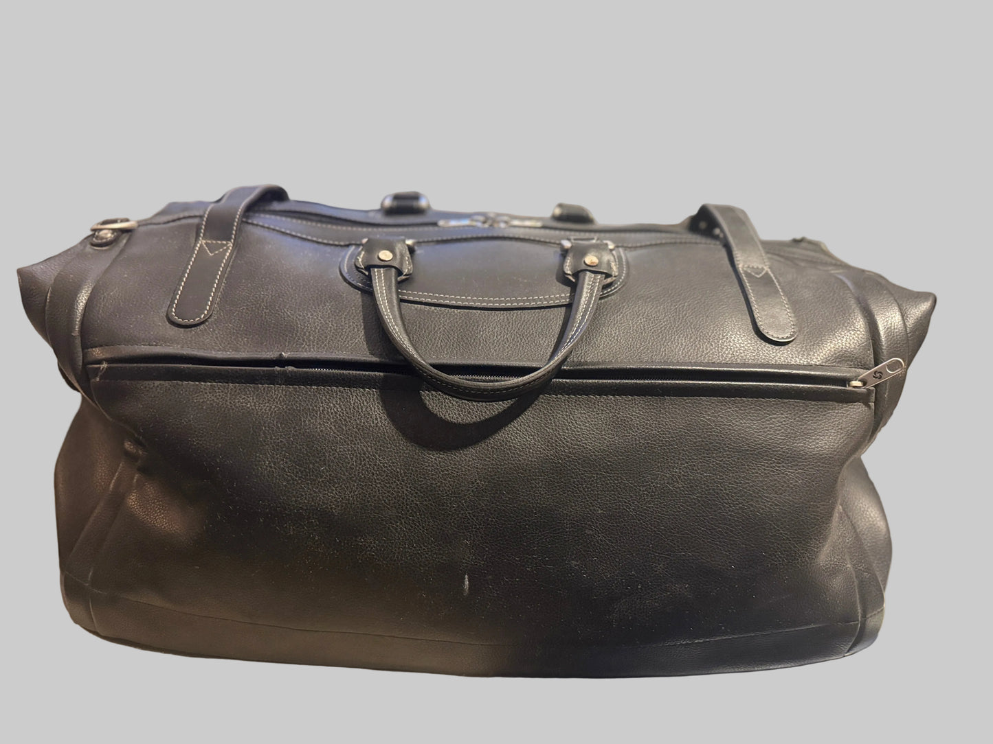 Black leather duffel bag on a table with a blurred background