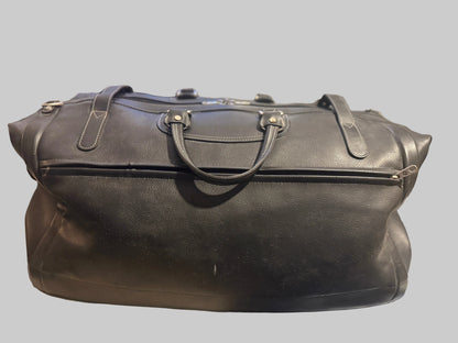 Black leather duffel bag on a table with a blurred background
