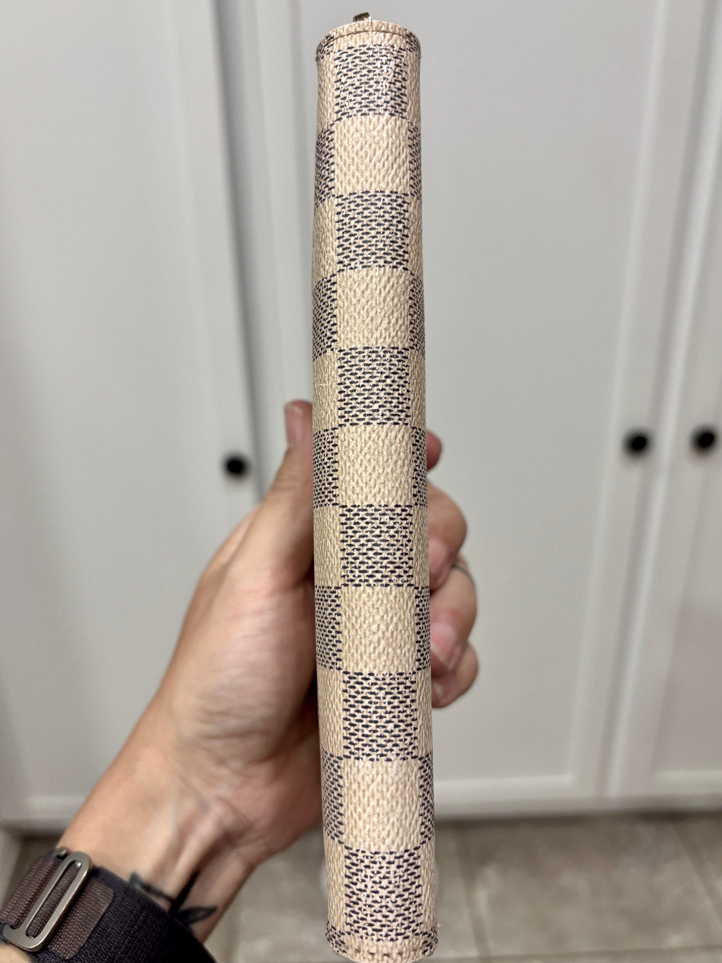 Hand holding a cylindrical woven object against a neutral background