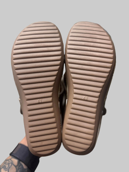Close-up of brown sandals with textured soles on a blurred background