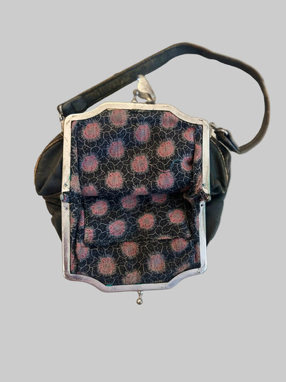 Small handbag with a patterned flap on a light wooden surface