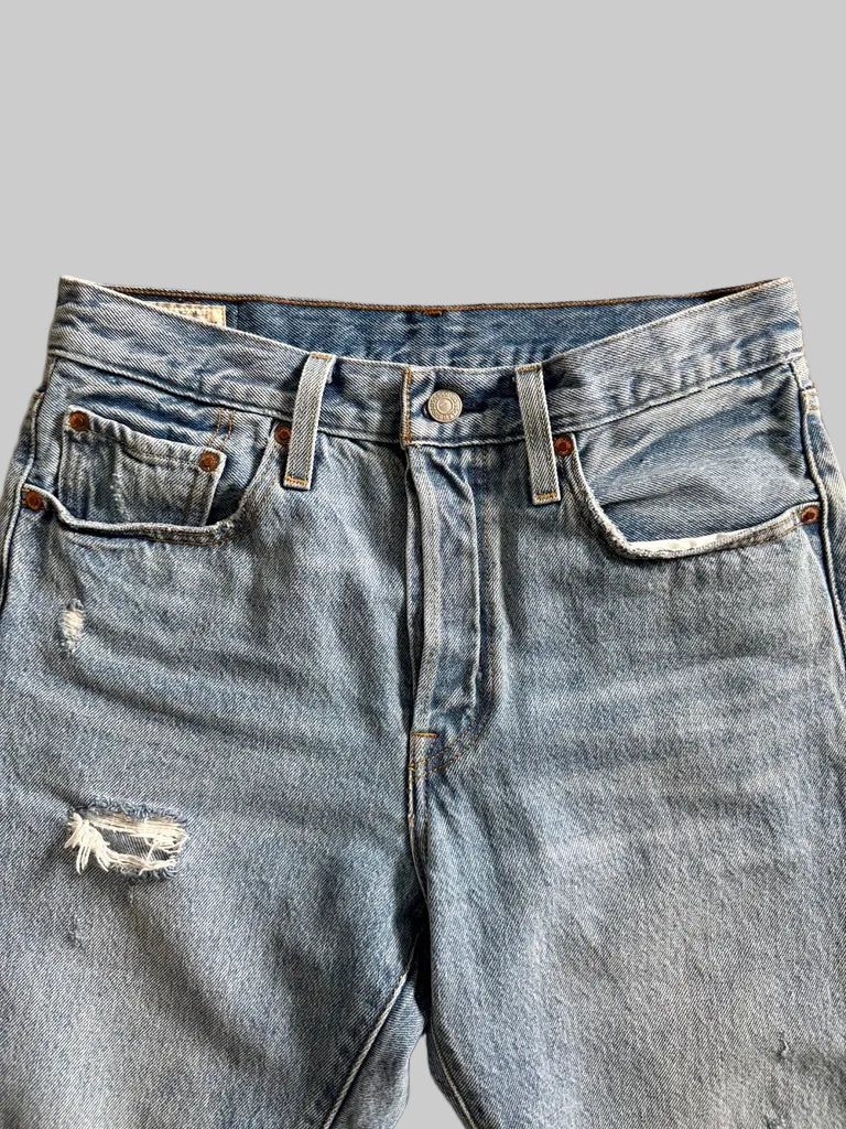 Pair of blue jeans with a slight distressing detail on a beige surface
