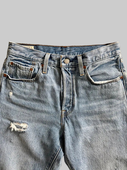 Pair of blue jeans with a slight distressing detail on a beige surface