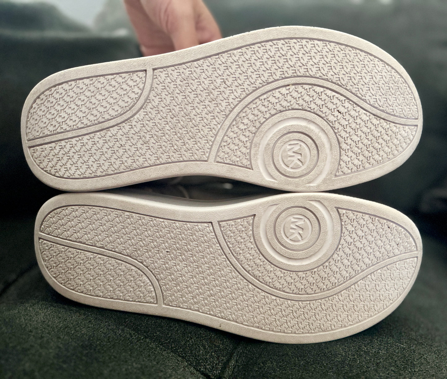Close-up of a beige shoe sole with a brand logo on a dark background