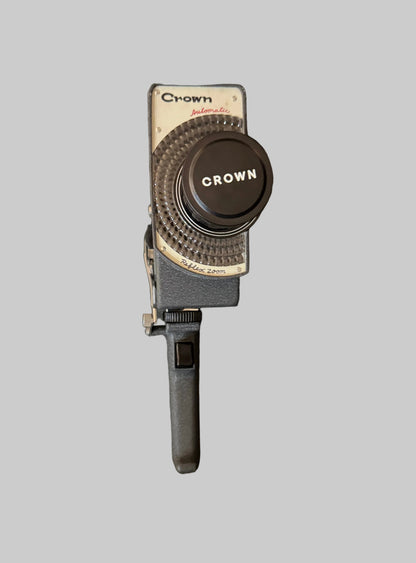 Vintage camera lens with 'Crown' branding on a dark surface
