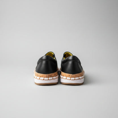 Pair of black and brown shoes on a light wooden floor.