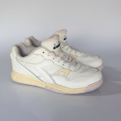 White sneakers with beige soles on a light gray surface in an indoor setting
