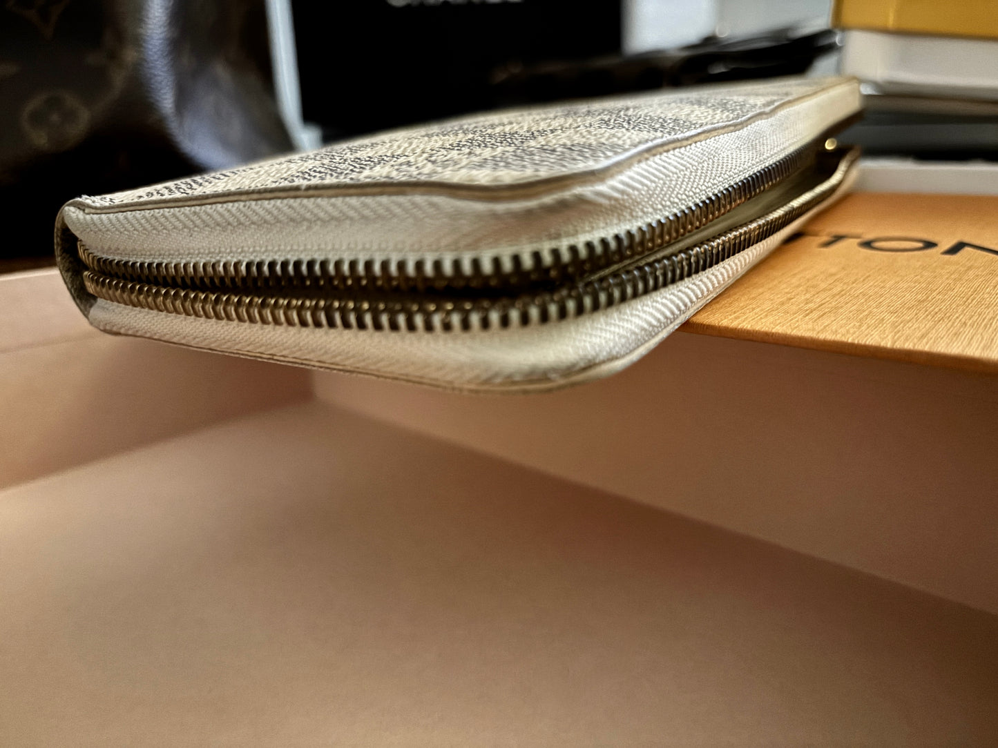 Silver clutch bag on a beige surface with a blurred background