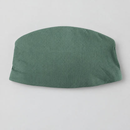 A sage green ribbed knit skirt or shorts laid flat on a textured gray blanket, with a white retail tag still attached.