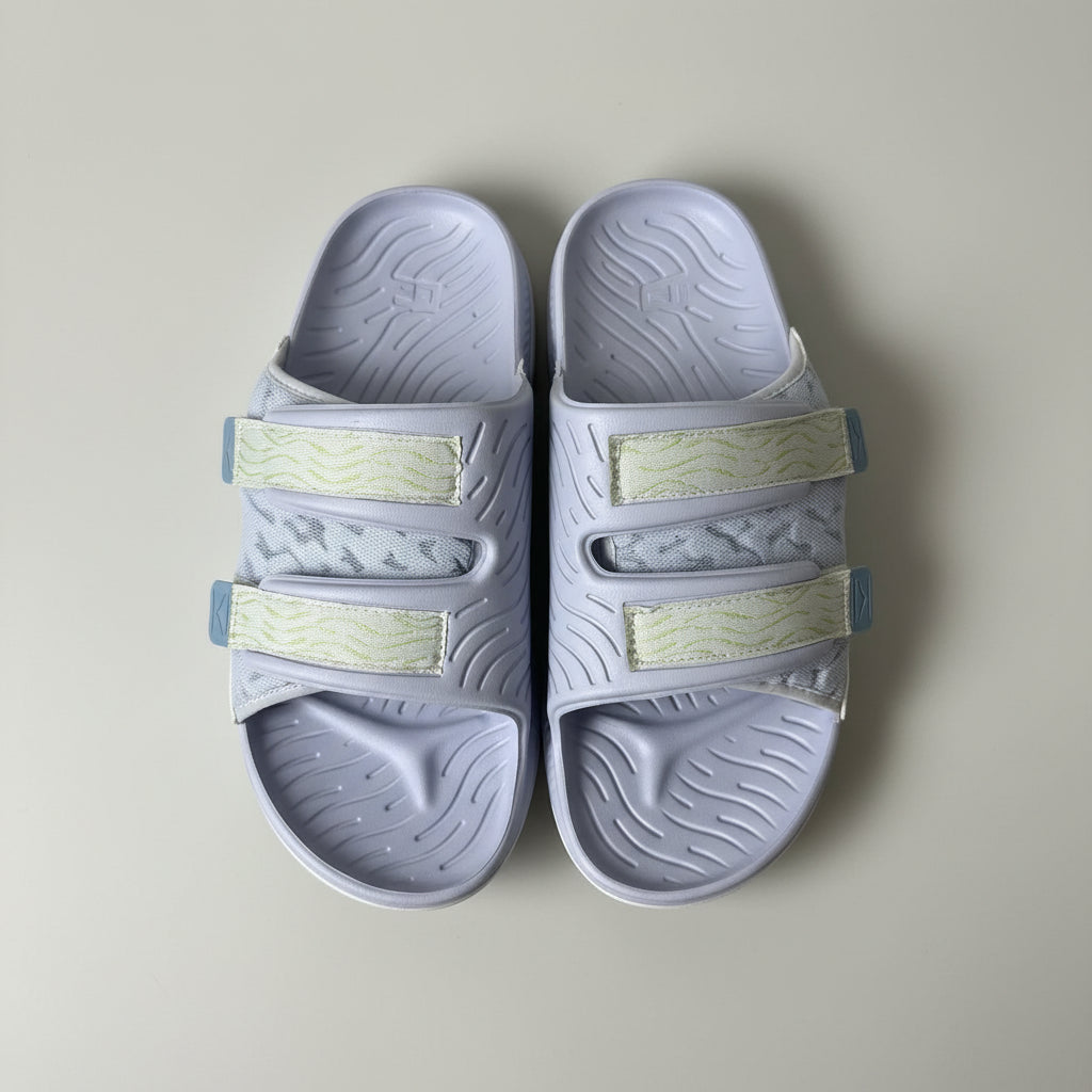 Pair of gray slides with light green straps on a beige background