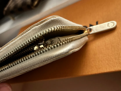 Close-up of a silver wallet with a zipper on a brown surface
