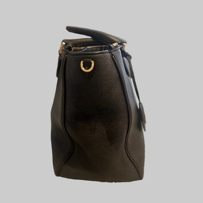 Black leather handbag on a textured surface with a blurred background