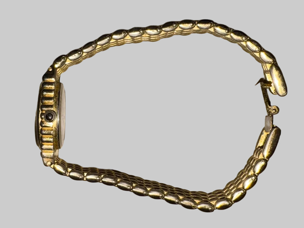 Gold bracelet on a light gray surface
