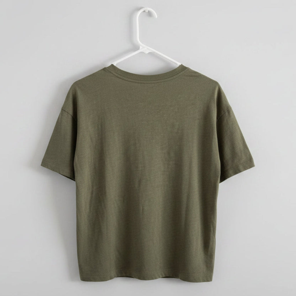 An olive green short-sleeve t-shirt hanging on a white plastic hanger against a textured off-white wall.