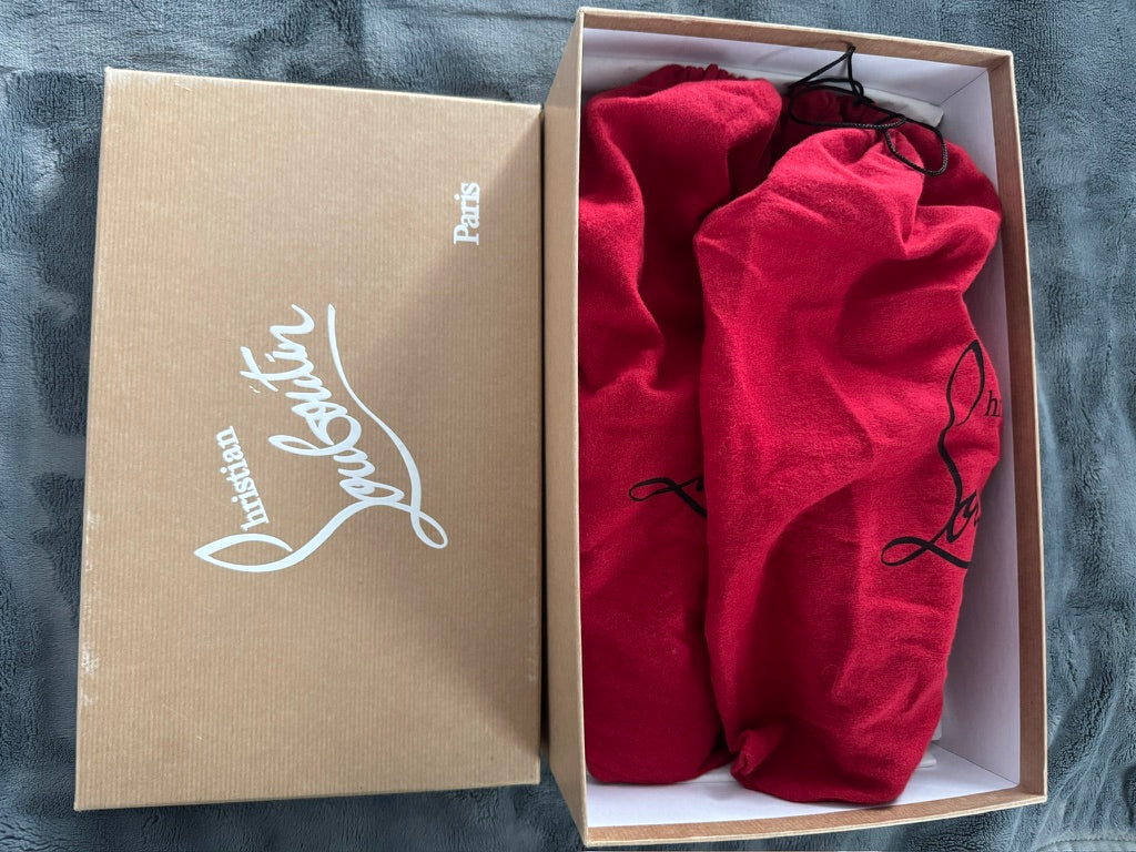 Red fabric in a Christian Louboutin box on a gray surface