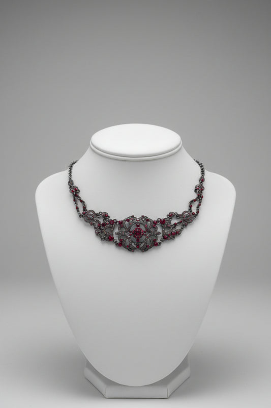 Decorative necklace with red stones on a white surface