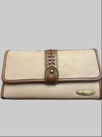 A beige pebbled leather wallet with brown trim and a braided strap detail, resting on a dark wooden surface.