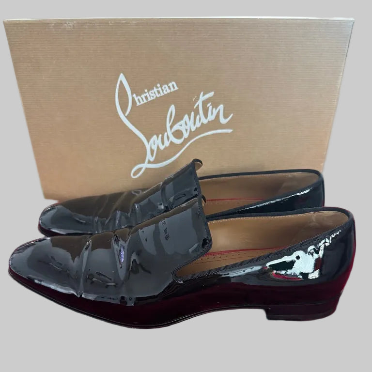 Black patent leather loafers with a shark design on a red Christian Louboutin branded surface.