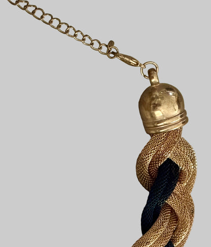 Close-up of a gold tassel with a chain on a light wooden surface