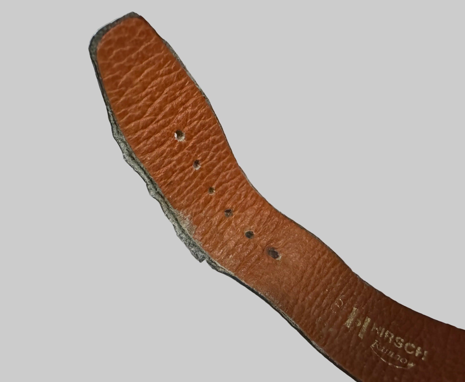 Brown leather belt with visible branding on a textured gray background