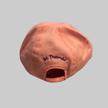 A dusty pink baseball cap with 'St. Thomas' embroidered in navy blue on the side, resting on a gray shaggy blanket.