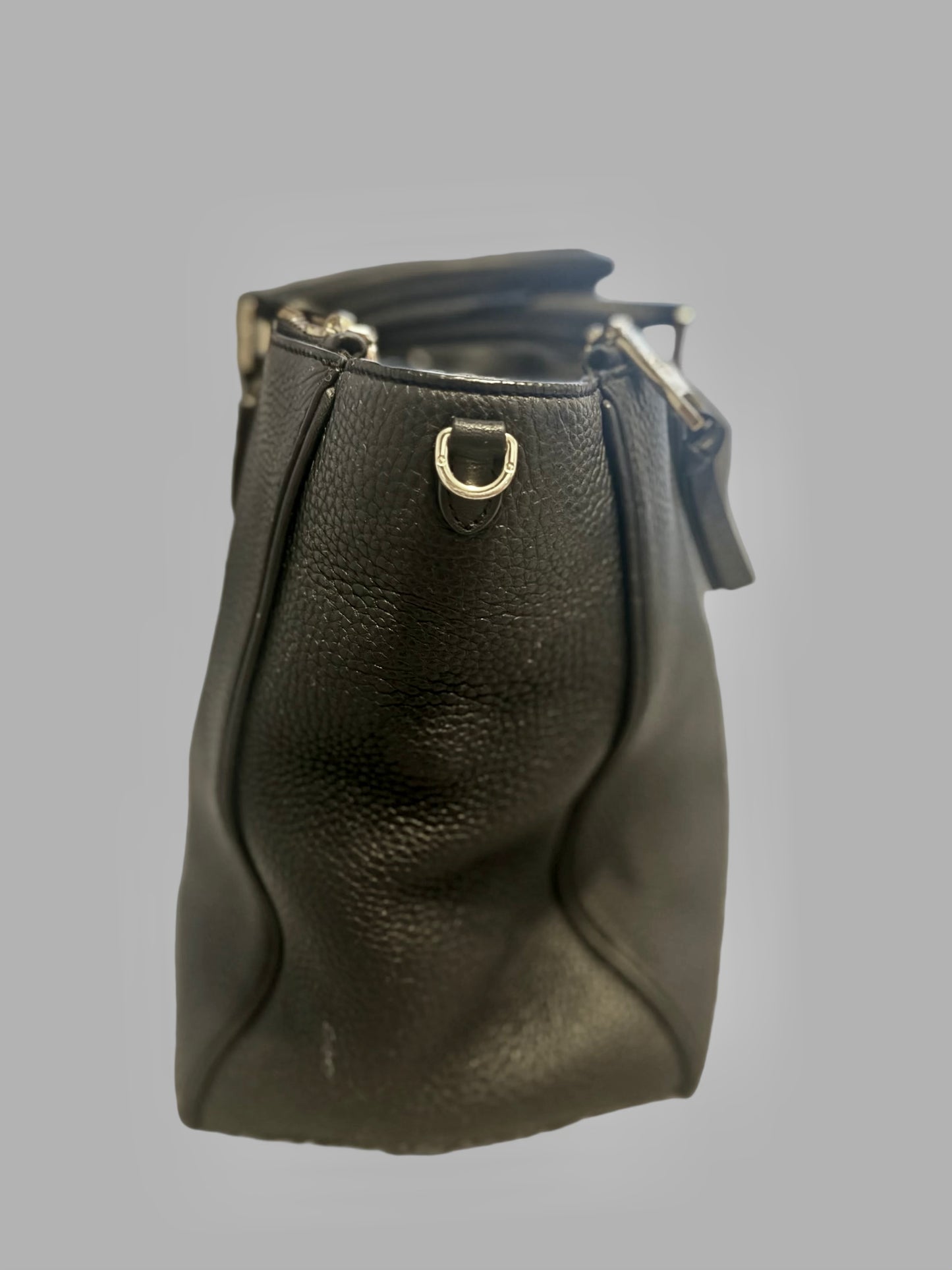 Black leather handbag with gold hardware on a gray background