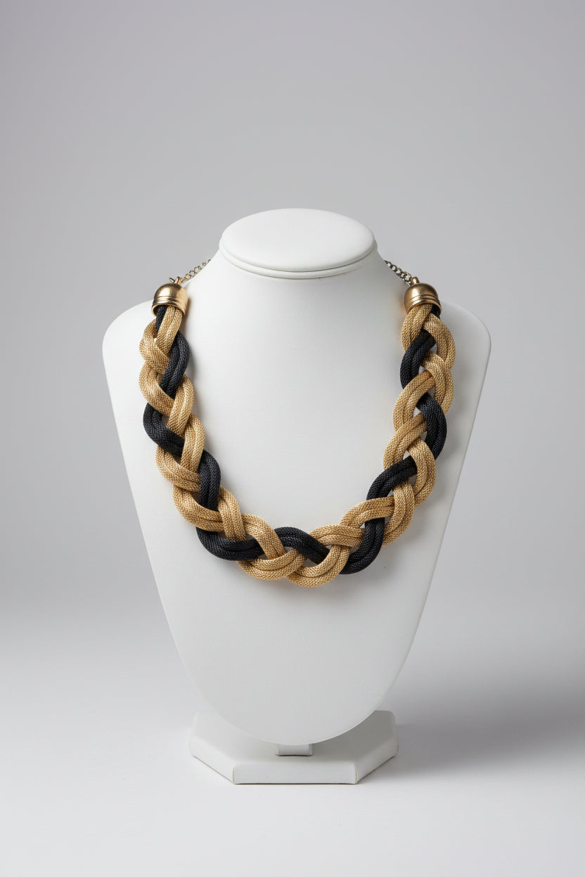 Braided necklace with gold and black strands on a light surface