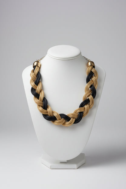 Braided necklace with gold and black strands on a light surface