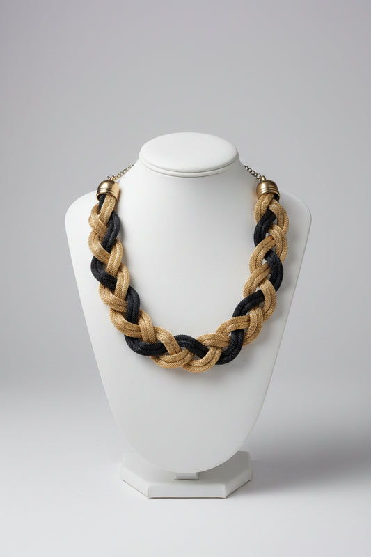 Braided necklace with gold and black strands on a light surface