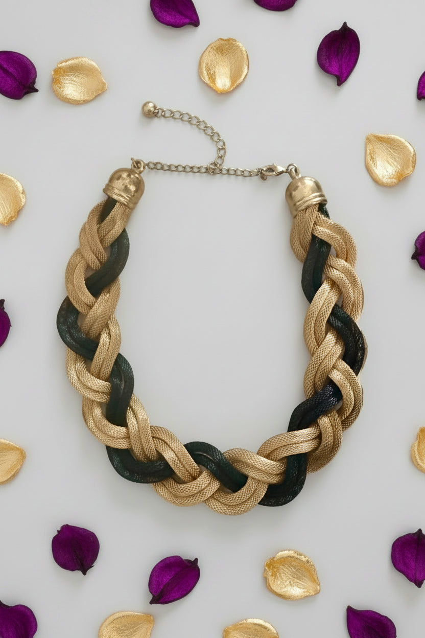Braided necklace with gold and black strands on a light surface.