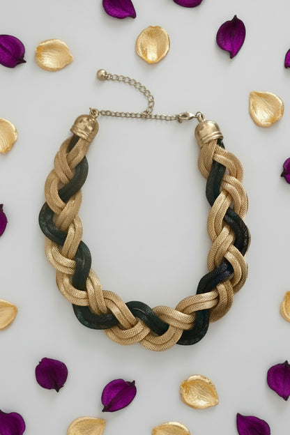 Braided necklace with gold and black strands on a light surface.
