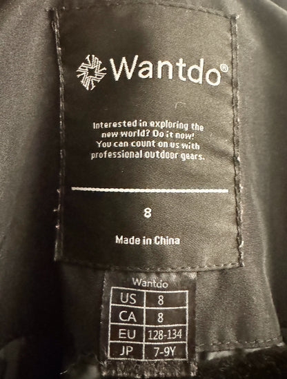 Close-up of a black Wantdo garment interior label showing the brand name, slogan, size 8, and country of origin, with a smaller size conversion chart below.