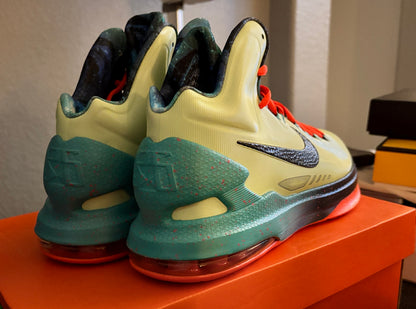 Pair of green and yellow sneakers on an orange surface with a neutral background