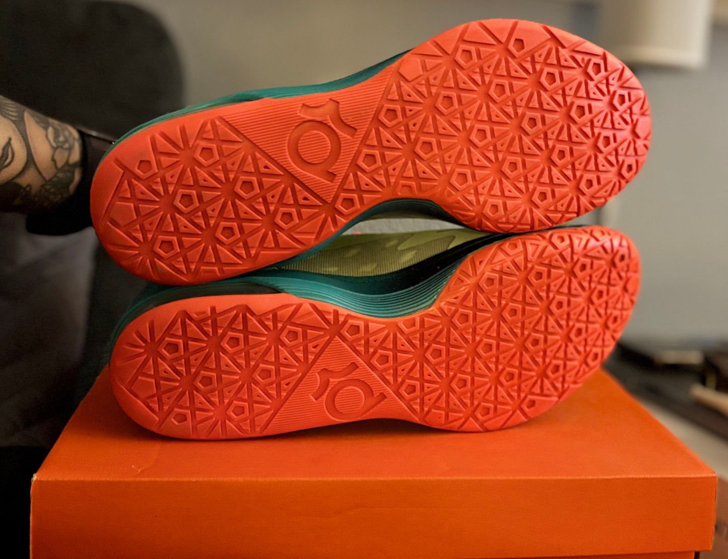 Close-up of orange athletic shoes with a geometric sole pattern on an orange box.