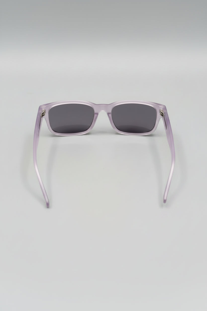Sunglasses with a clear frame and dark lenses on a light gray background