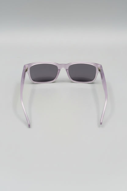 Sunglasses with a clear frame and dark lenses on a light gray background
