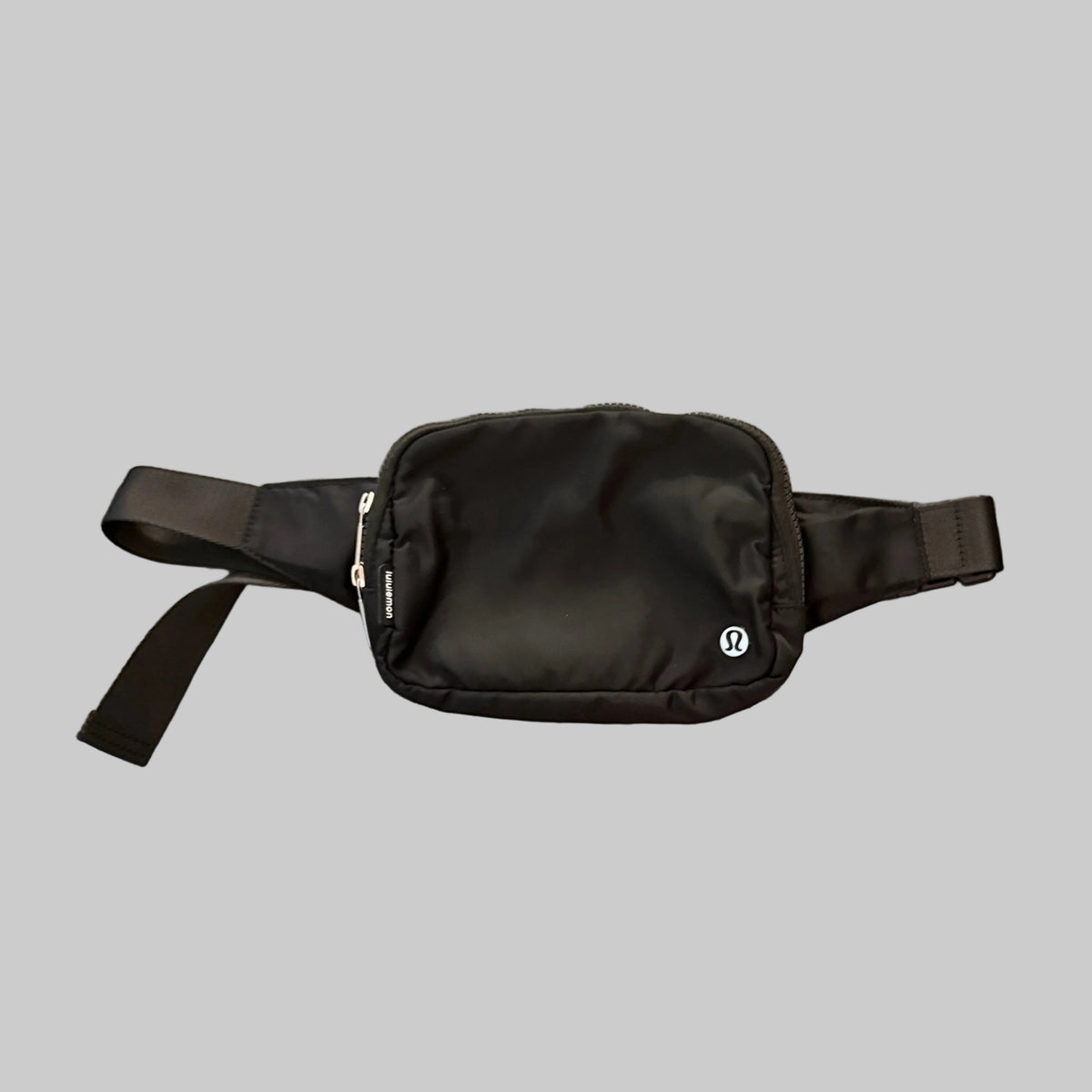 A black nylon crossbody bag with a small white circular logo